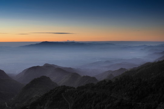 Mountain view misty morning of top hills around with sea of fog with red and yellow sun light in the sky background, sunrise at Doi Ang Khang, Monzone view point, Chiang Mai, Thailand.