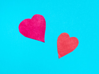 two different hearts cut from red papers on blue