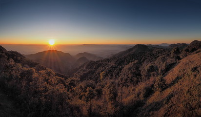 Mountain view misty morning of top hills with yellow sun light in the sky background, sunrise at Doi Ang Khang, Monzone view point, Chiang Mai, Thailand.