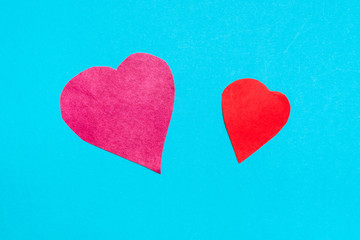 Obraz premium two hearts cut from red papers on blue paper