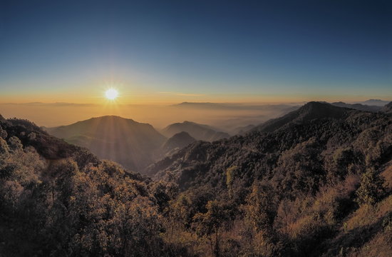 Mountain view misty morning of top hills with yellow sun light in the sky background, sunrise at Doi Ang Khang, Monzone view point, Chiang Mai, Thailand.