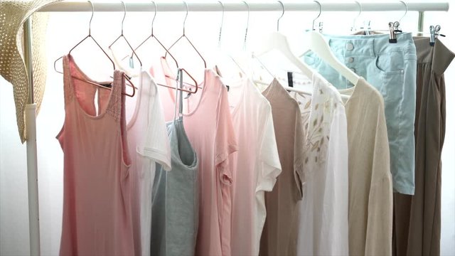 clothing, fashion, style and people concept - rack with stylish light pastel colors woman’s clothes