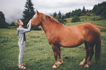 Young beautiful girl hugging horse at nature. Horse lover.