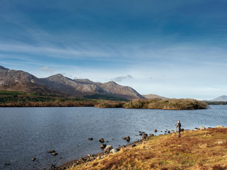 Woman looking at landscape, Derryclare lake, Connemara National park, Ireland, Blue cloudy sky, mountains.