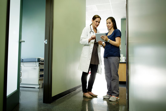 Woman doctor and nurse looking at tablet