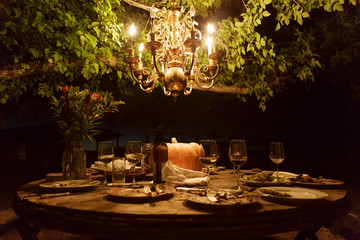 Outdoor dining table with rustic decor and chandelier