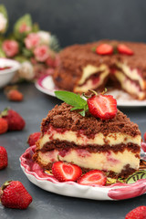 Chocolate cake with cottage cheese with strawberries is located on a dark background, a piece of cake is located in the foreground on a plate