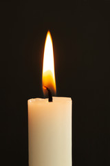 Burning candle light close up on black background