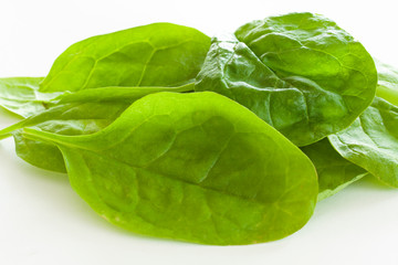 Pile of fresh green spinach leaves on white background. Close up image.