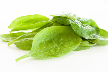 Pile of fresh green spinach leaves on white background. Close up image.