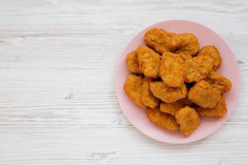 Chicken nuggets on a pink plate on a white wooden background, top view. Overhead, from above, flat lay. Copy space.