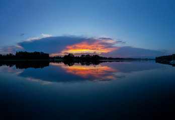Zachód słońca nad jeziorem Kalwa w Polsce. Odbicie nieba w wodzie.