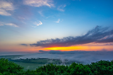 Fototapeta na wymiar Sunrise on a foggy summer morning over the village
