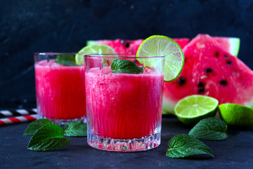 Watermelon smoothie and slices with lime on dark background. Top view with copy space.