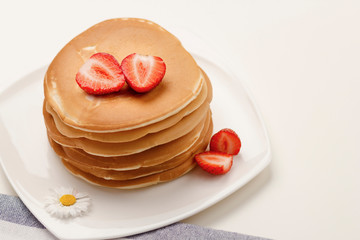 Homemade breakfast. American style pancakes served with fresh strawberry  on white table and towel.