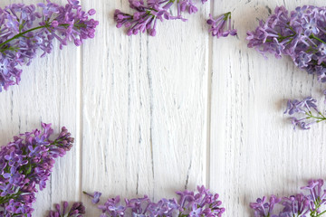 Frame for a banner of lilac flowers on a white wooden background. Background with spring flowers....