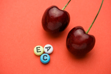 Close up of letters indicating the vitamins contained in cherries near the two berries.