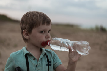 A little boy drinks water from a bottle.