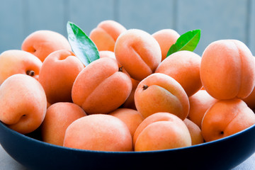 Ripe apricots in a plate with green leaves