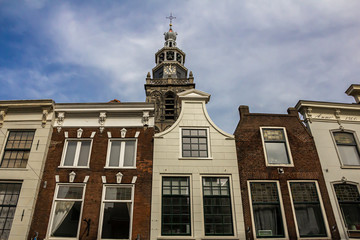Gouda, Holland, Netherlands, April 23, 2019. The market square in Gouda old town, a street of dutch style facades of houses and view of the bell tower of Sint-Janskerk church (longest in the Netherlan
