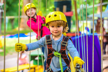 Happy little boyn calling while climbing high tree and ropes. Eco Resort Activities. Go Ape...