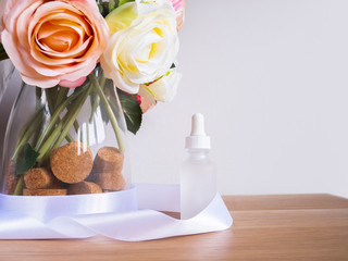 Sample of skincare serum oil with roses on light backdrop. Facial beauty cosmetic spa product. Natural cosmetology concept skin treatment. Dropper of essential oil, aromatherapy essence