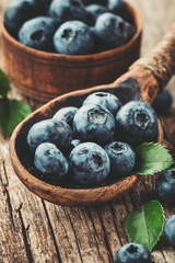 Blueberries in wooden spoon on old wood table. Healthy eating and nutrition concept.