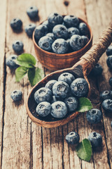 Blueberries in wooden spoon on old wood table. Healthy eating and nutrition concept.