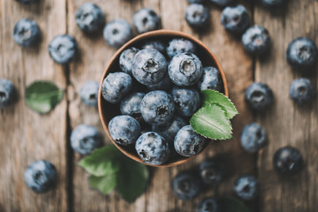 Freshly picked blueberries in wooden bowl on wooden background. Healthy eating and nutrition.