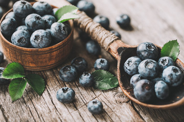 Blueberries in wooden spoon on old wood table. Healthy eating and nutrition concept.