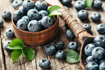 Blueberries in wooden spoon on old wood table. Healthy eating and nutrition concept.