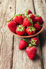Freshly picked Strawberry in wooden bowl on wooden background. Healthy eating and nutrition.