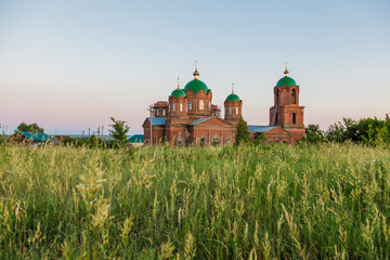 Fototapeta na wymiar Old red brick church with green domes