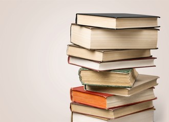 Collection of old books vertical stack on beige background