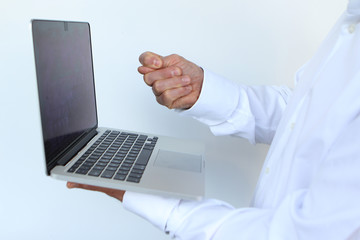 businessman in a white shirt with a laptop in hand, showing a blow to the monitor, close-up, copy...
