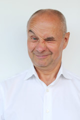 bald old man in a white shirt showing grimaces, winks, smiling, close-up
