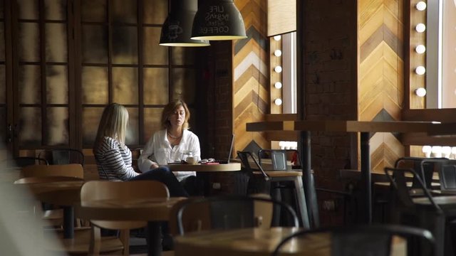 Business Lady Consulting her Female Client in a modern Coffee House. Informal Business Meeting Outside Office. Lifestyle and Business People Concept