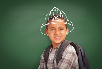Young Hispanic Student Boy Wearing Backpack Front Of Blackboard with Fireman Helmet Drawn In Chalk Over Head