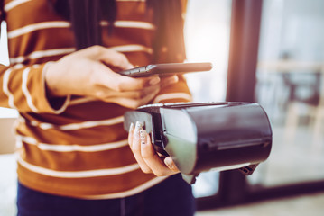 Young woman cashier accepting payment over nfc technology.