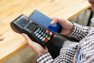 Young man with NFC technology payment via terminal machine.