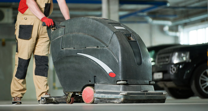 Worker With Machine Cleaning Floor In Parking Garage.