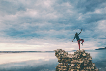 The girl stands on a pile of stones and looks at the sea.