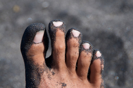 Male Feet Covered By Black Sand