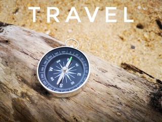 Travel texture with a compass on the bench of sandy beach background.