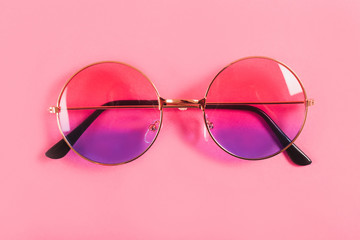 Round summer duotone sunglasses on pink background.