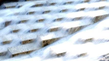 Water flowing down in a series of cascades, in long exposure.