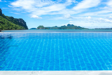 Swimming pool looking at sea view mountain and clouds in background.
