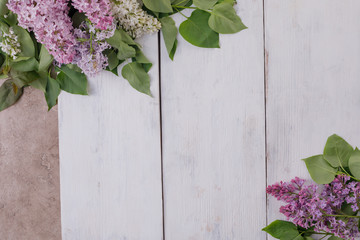 A plate and a decor of flowers on a background of white-painted wooden boards. Vintage background with lilac flowers and a place under the text. View from above. Cutlery.