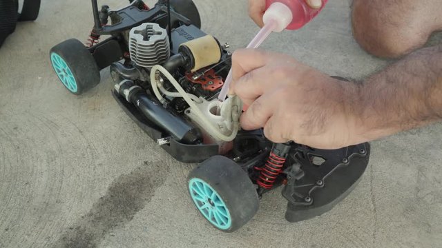 Adding red colored fuel to the remote controlled rc nitro car tank before the race