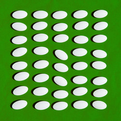 White pills on green background.